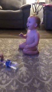 A baby is surprised by flipping a water bottle